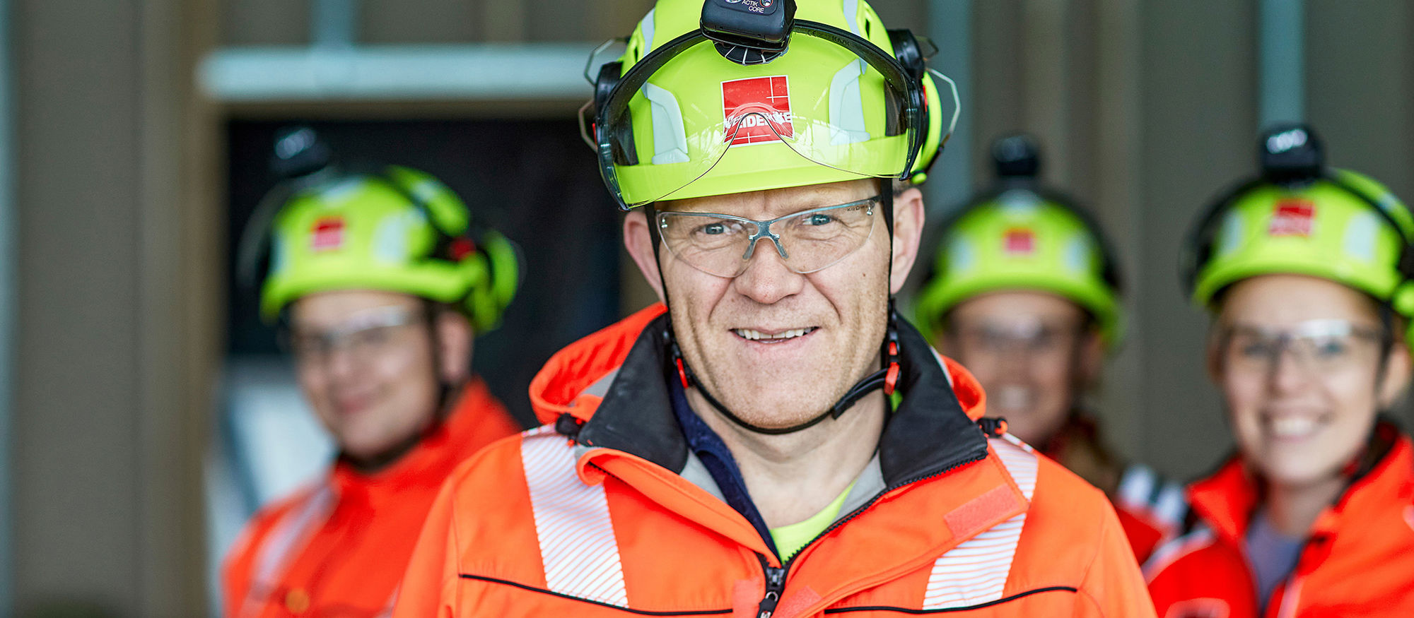 Group of Veidekke employees wearing helmets and high-vis clothing. Photo.