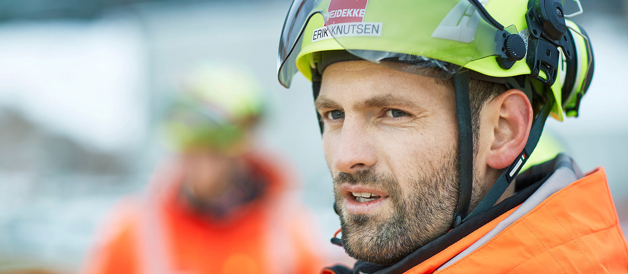 Man wearing yellow helmet looking to the left. Photo.