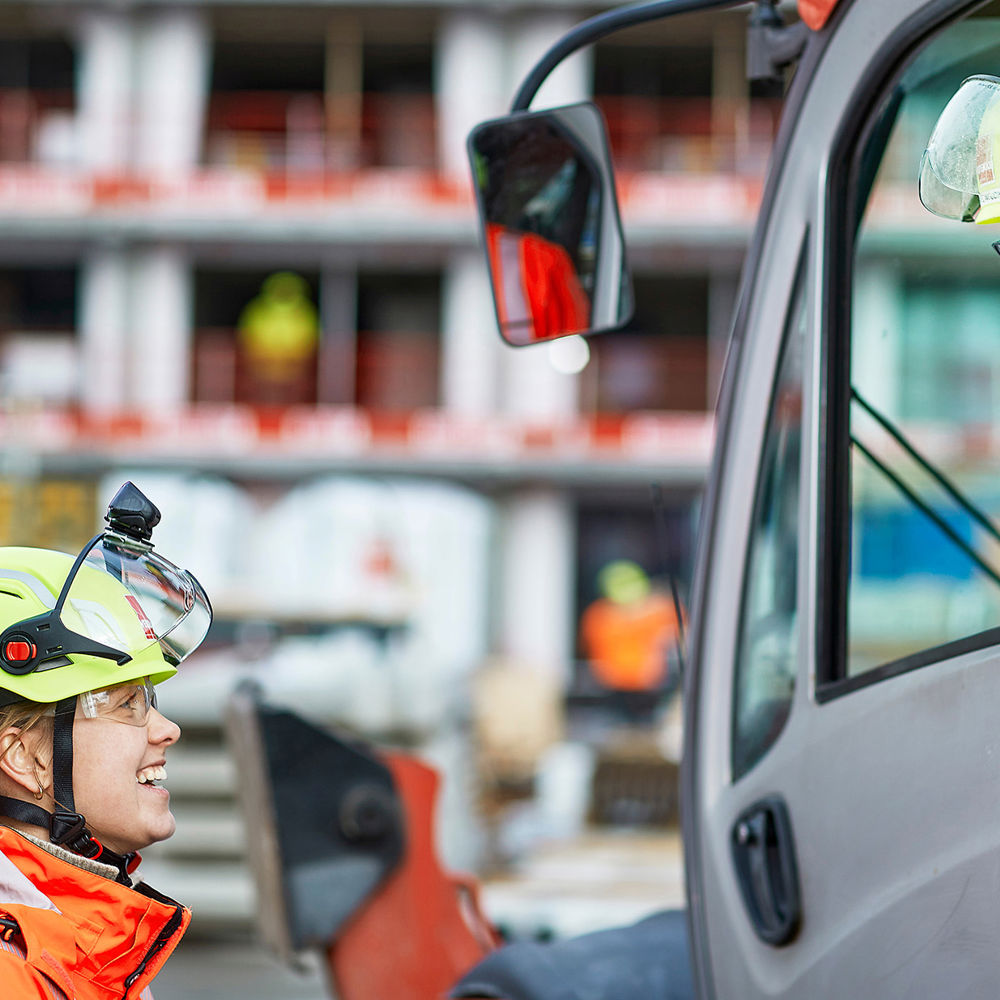 Woman talking to a man in a forklift. Photo.