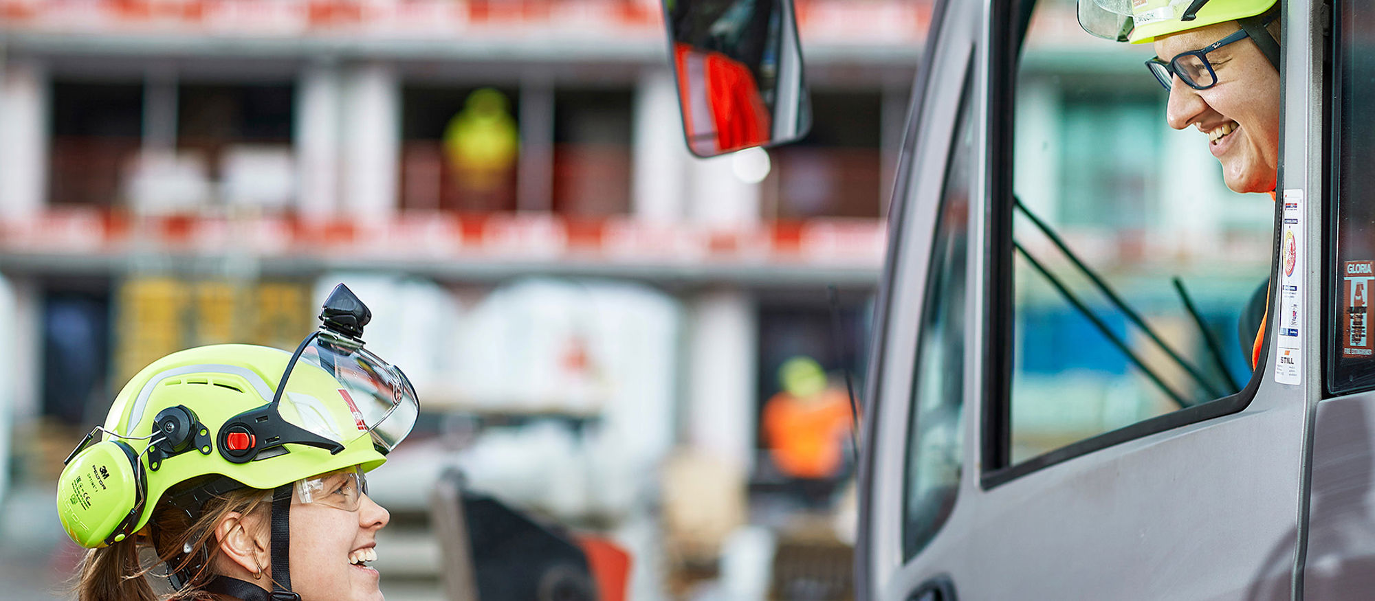 Woman talking to a man in a forklift. Photo.