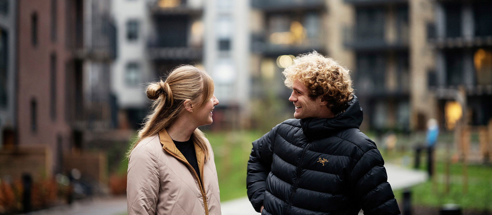 A lady and a man are talking outdoors. Photo.