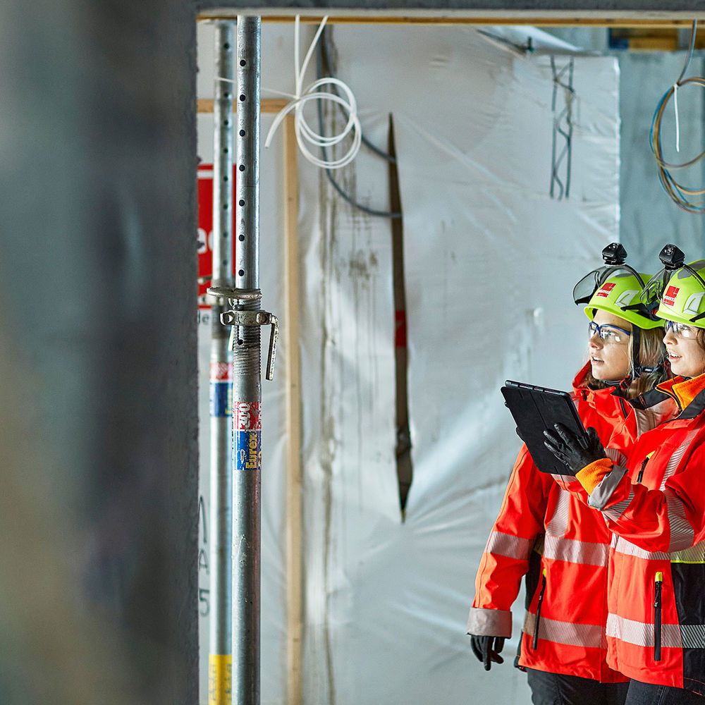 Two women on construction site, holding Ipad. Photo.