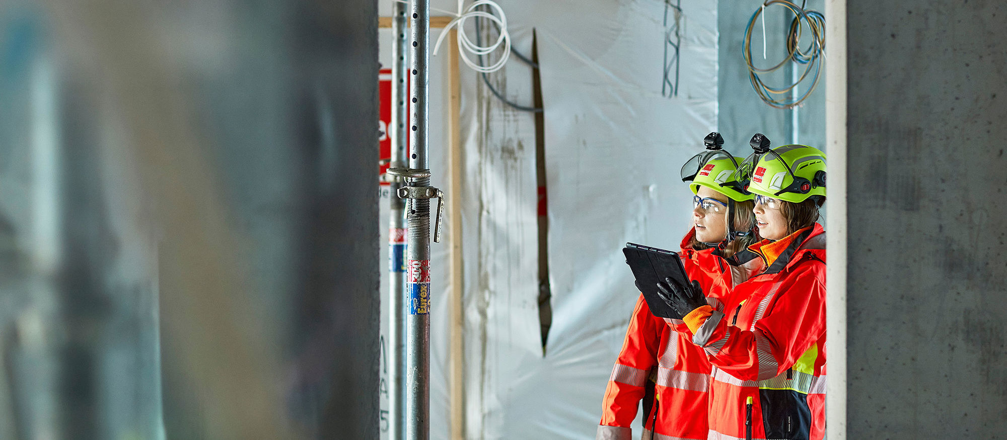 Two women on construction site, holding Ipad. Photo.