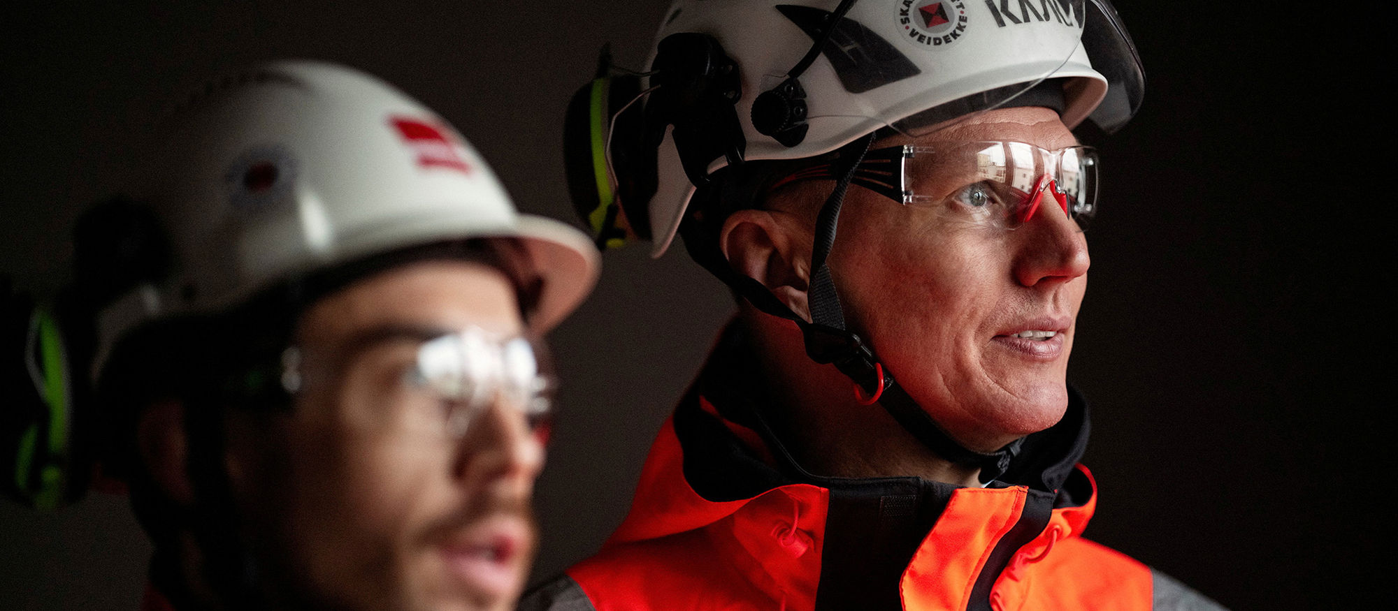 Two male workers looking at something. Wearing helmet and goggles. Photo.